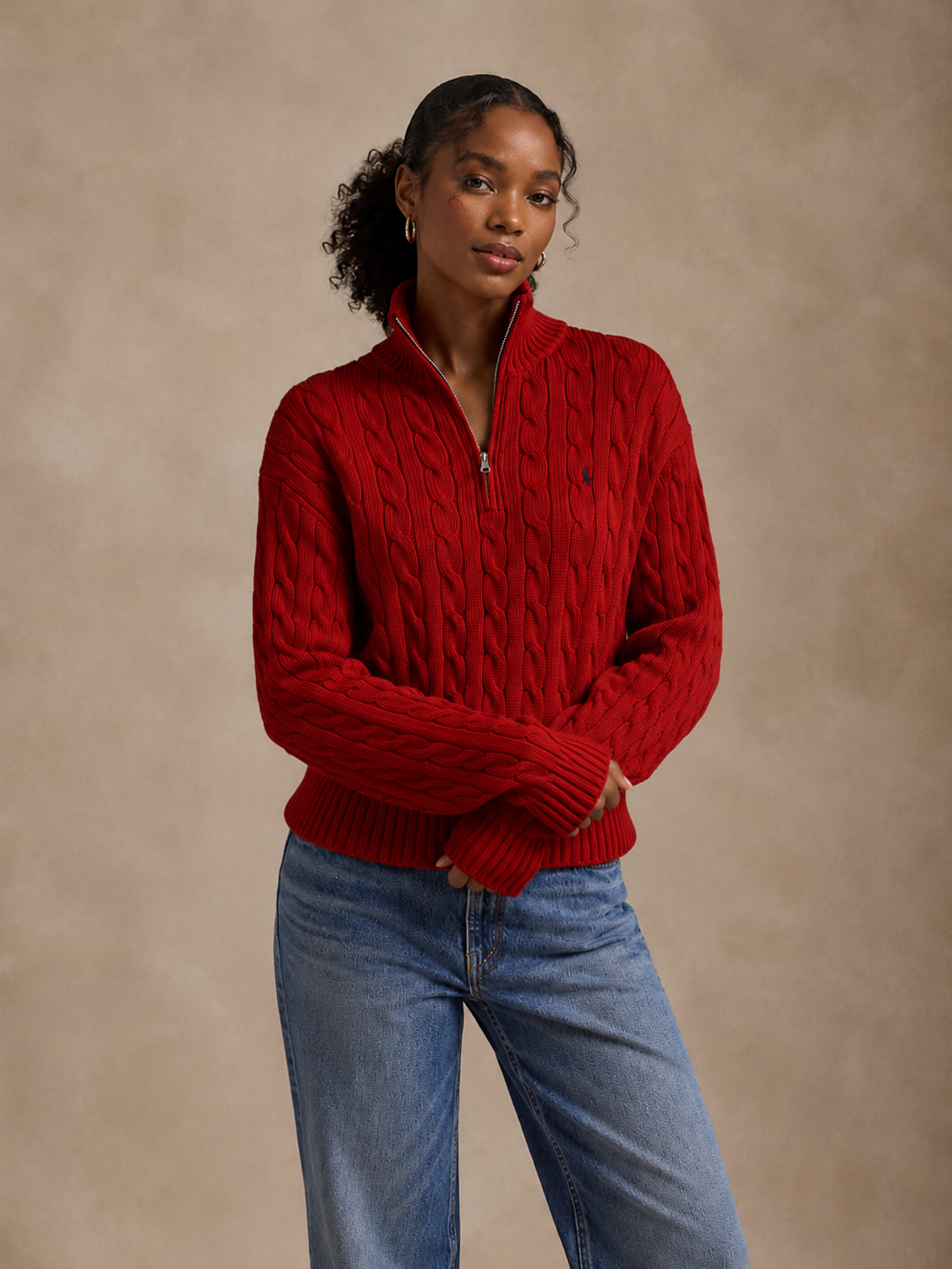 Woman wearing a red cable-knit quarter zip with relaxed denim